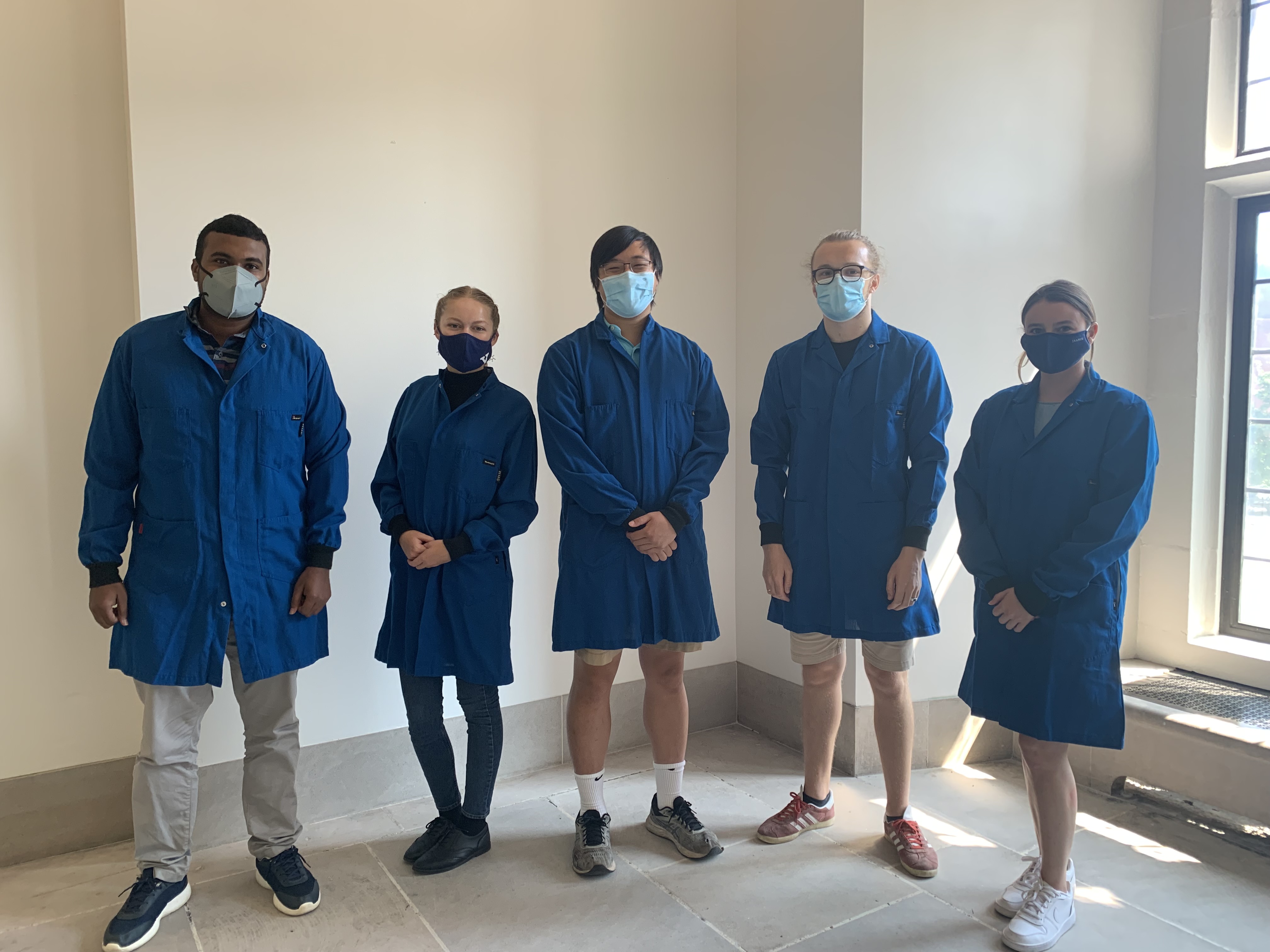 five people wearing blue lab coats