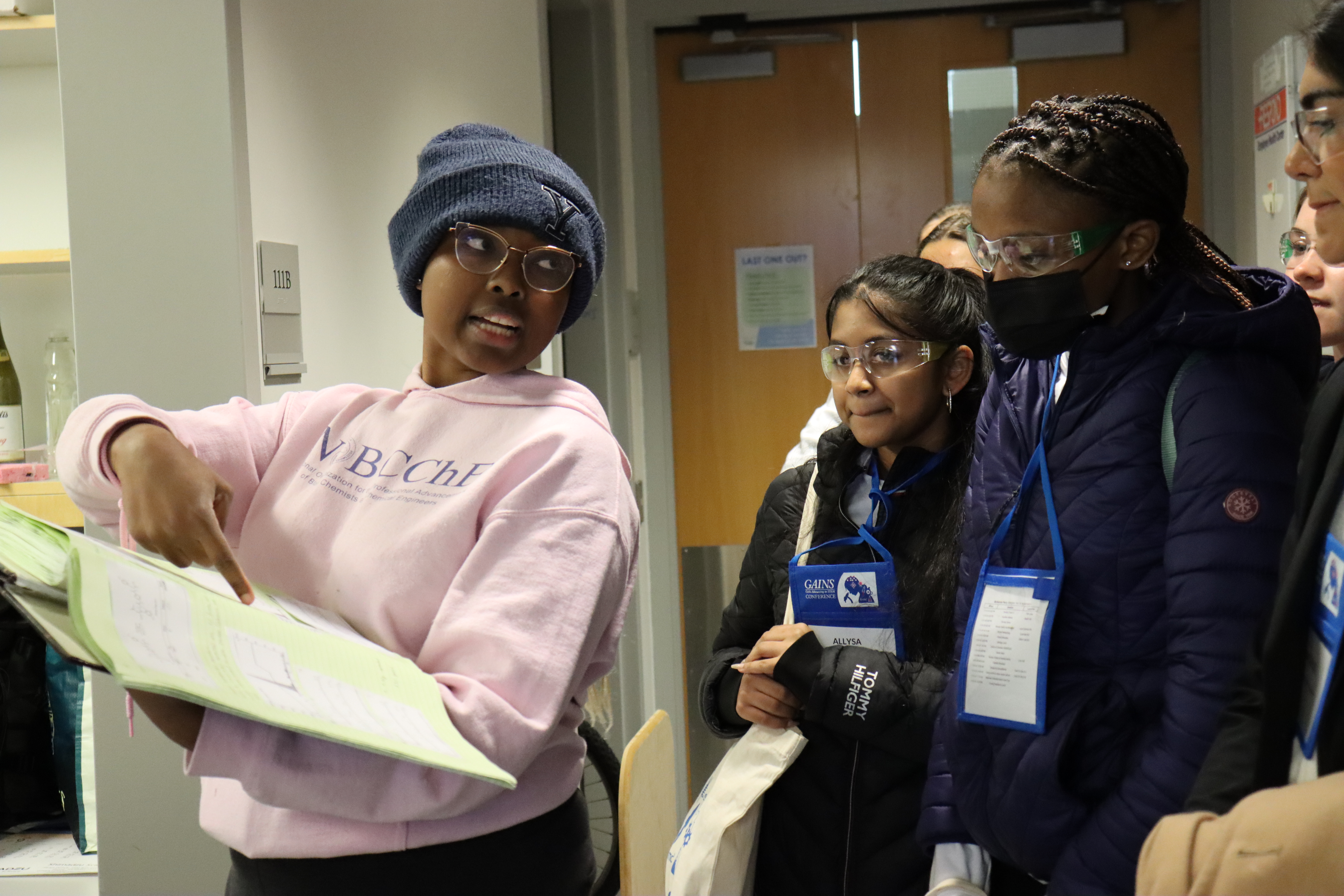 lady pointing to book with girls looking on