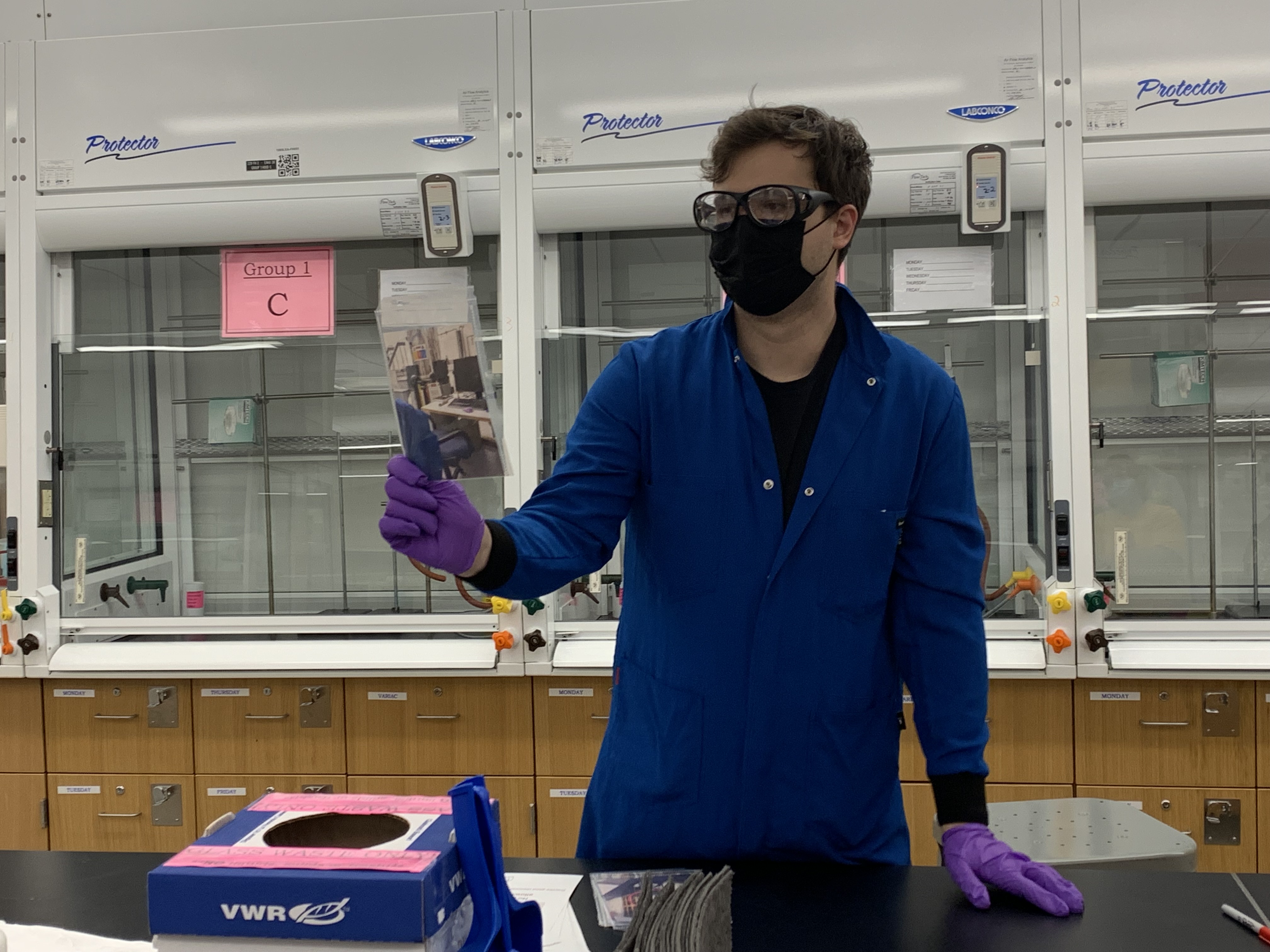 man blue lab coat holding paper