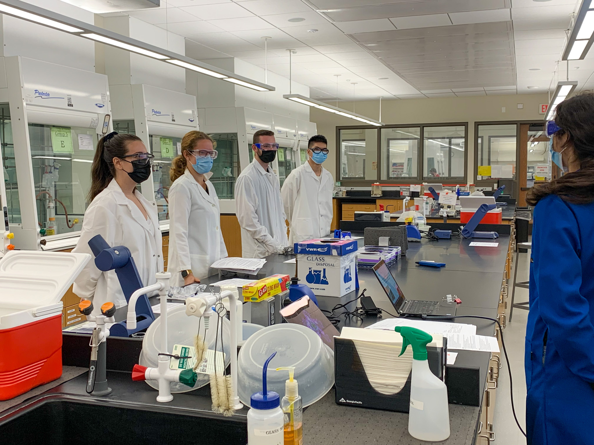 people in white lab coats at bench