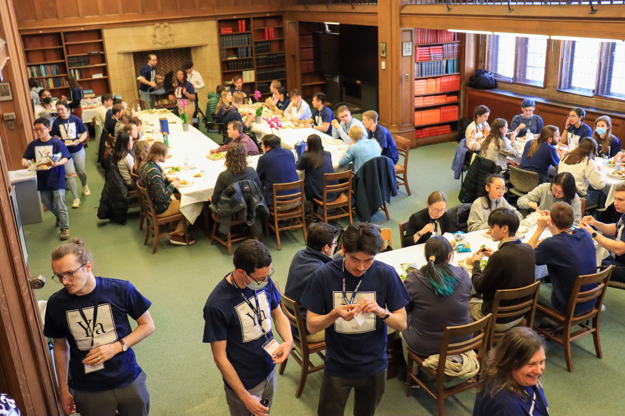 Crowd of people standing and sitting eating at tables