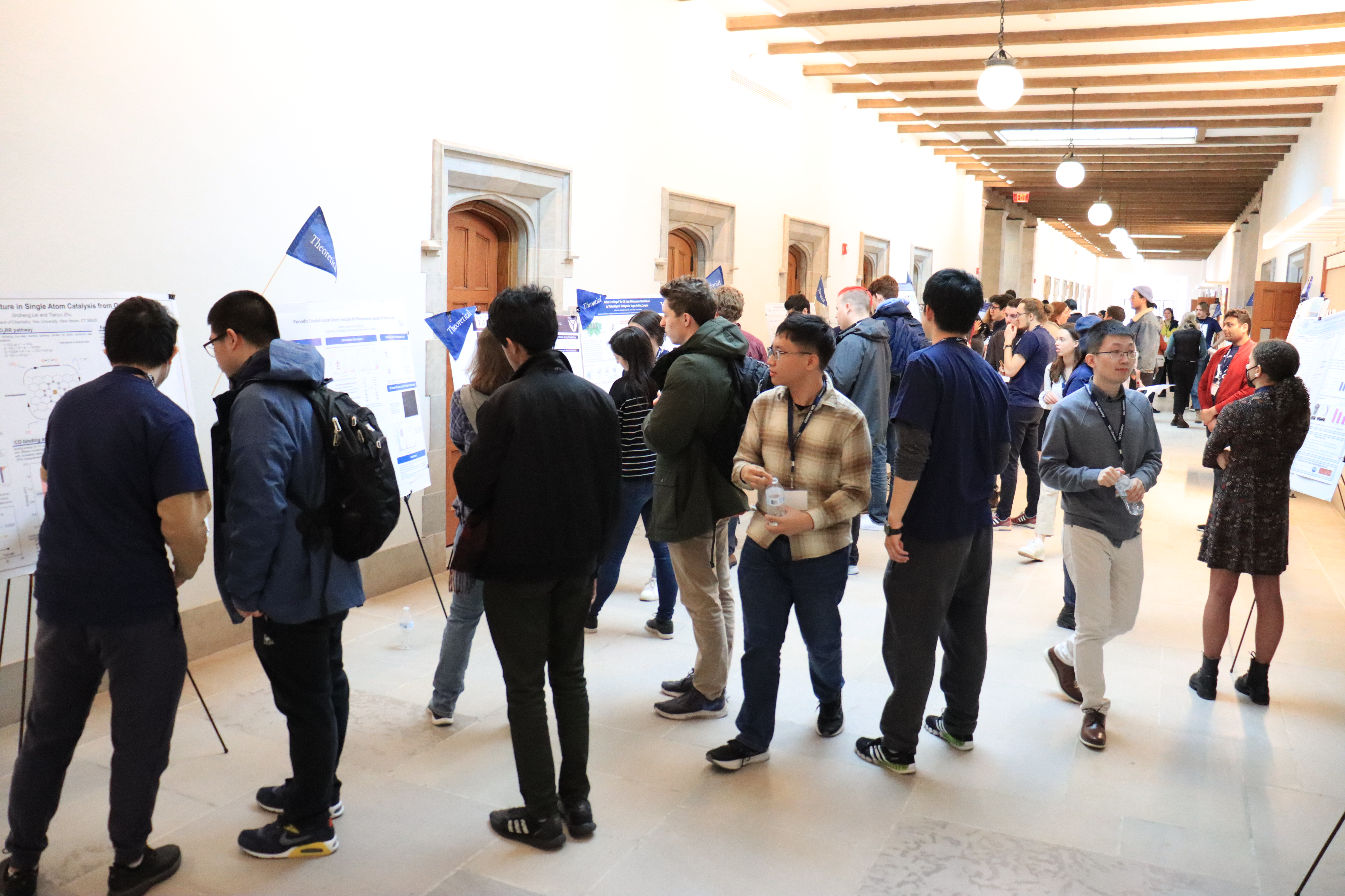 crowd of people looking at posters in hallway