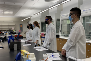 students in lab coats at bench