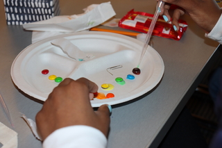 Hands using pipette to drop water onto candy