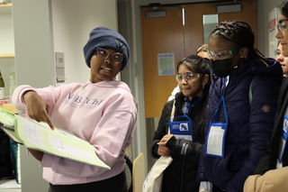 lady pointing to book with girls looking on