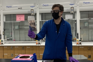 man blue lab coat holding paper