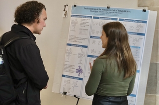 Man and woman chatting and looking at research poster