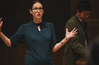 Woman pointing and gesturing in front of blackboard