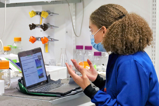 woman in lab coat gesturing to a laptop