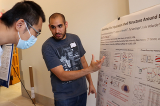 man gesturing towards poster