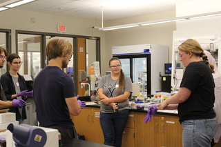 people in lab putting on gloves