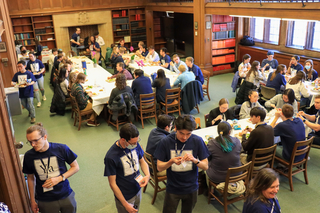 Crowd of people standing and sitting eating at tables