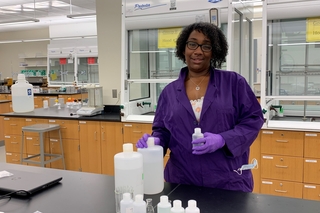 woman in lab coat standing near bottles