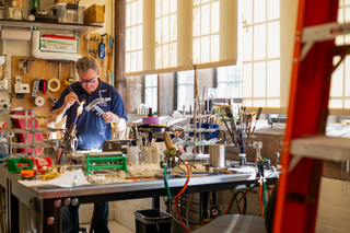 man using glassblowing instrument in shop
