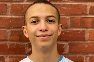 young man standing against brick wall