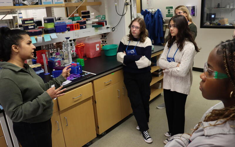 Woman talking to group of girls by a lab bench