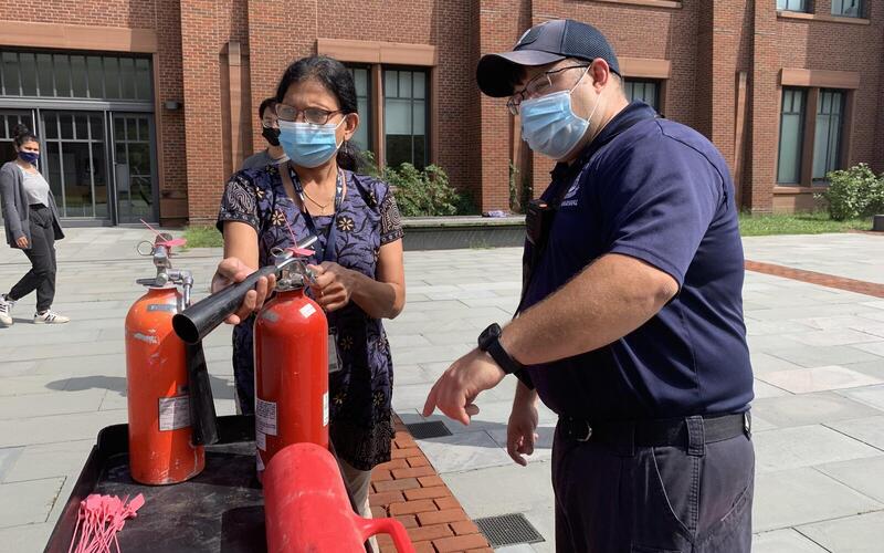 Man teaching woman how to use fire extinguisher