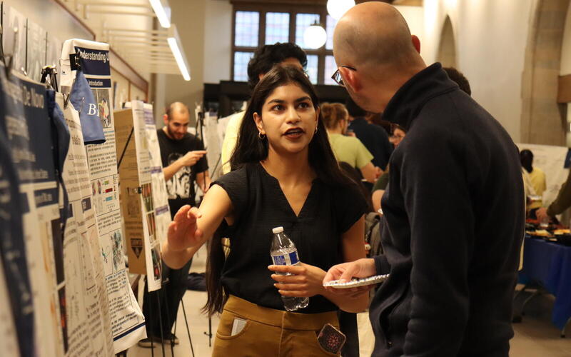 woman explaining to man by research poster