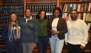 five people standing in front of bookcase