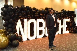 man standing in front of sign and balloons