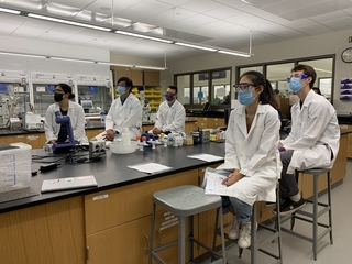 students sat at chemistry lab bench