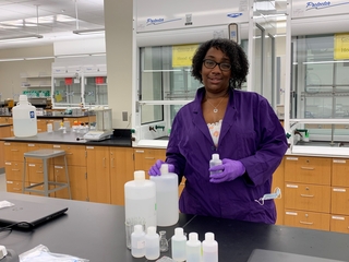 woman in lab coat standing near bottles