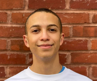 young man standing against brick wall