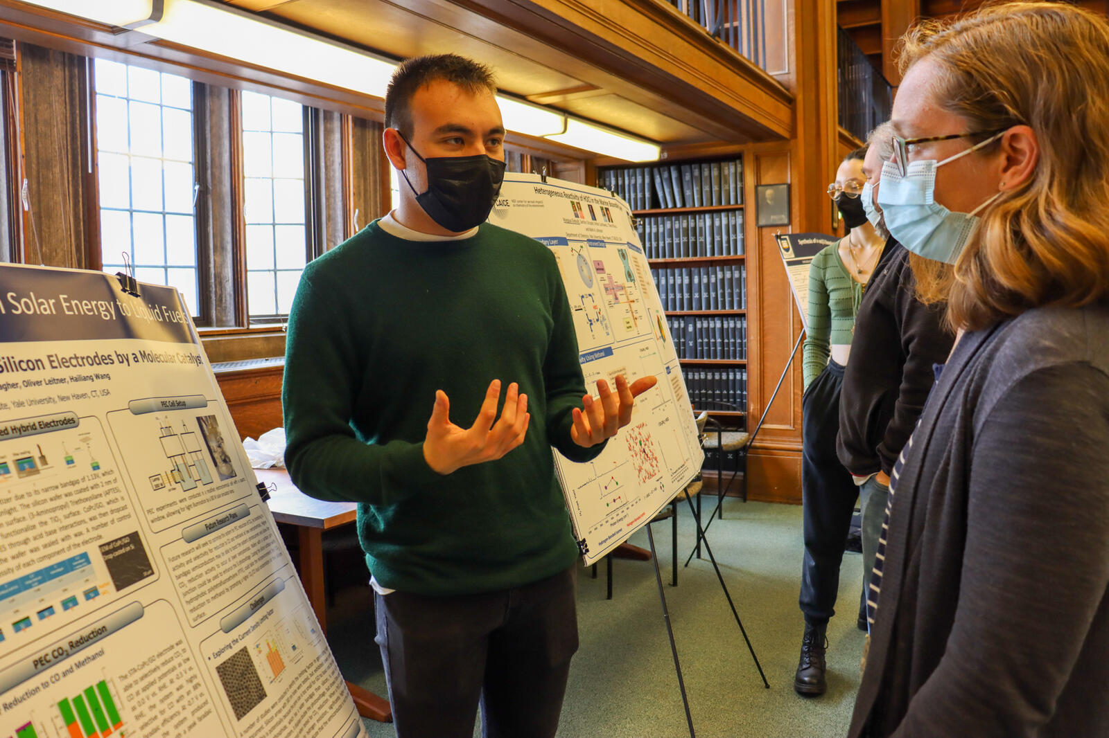 Man gesturing next to poster talking to woman