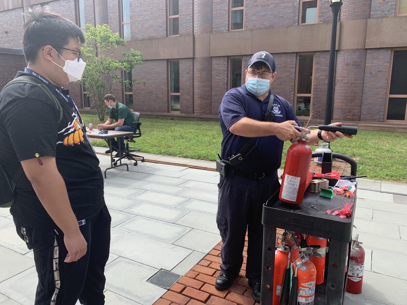 Man teaching man how to use fire extinguisher