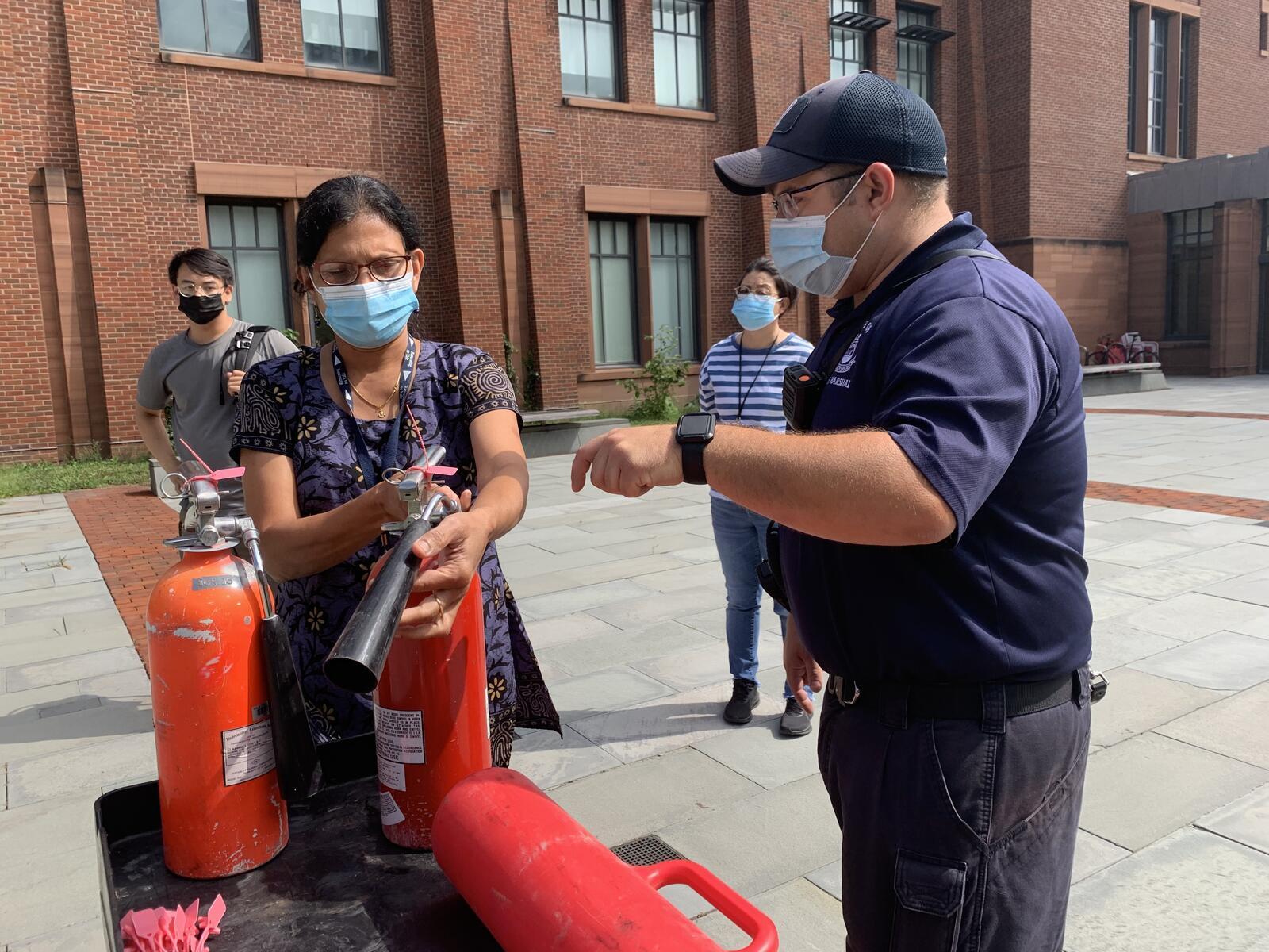 Man teaching woman how to use fire extinguisher