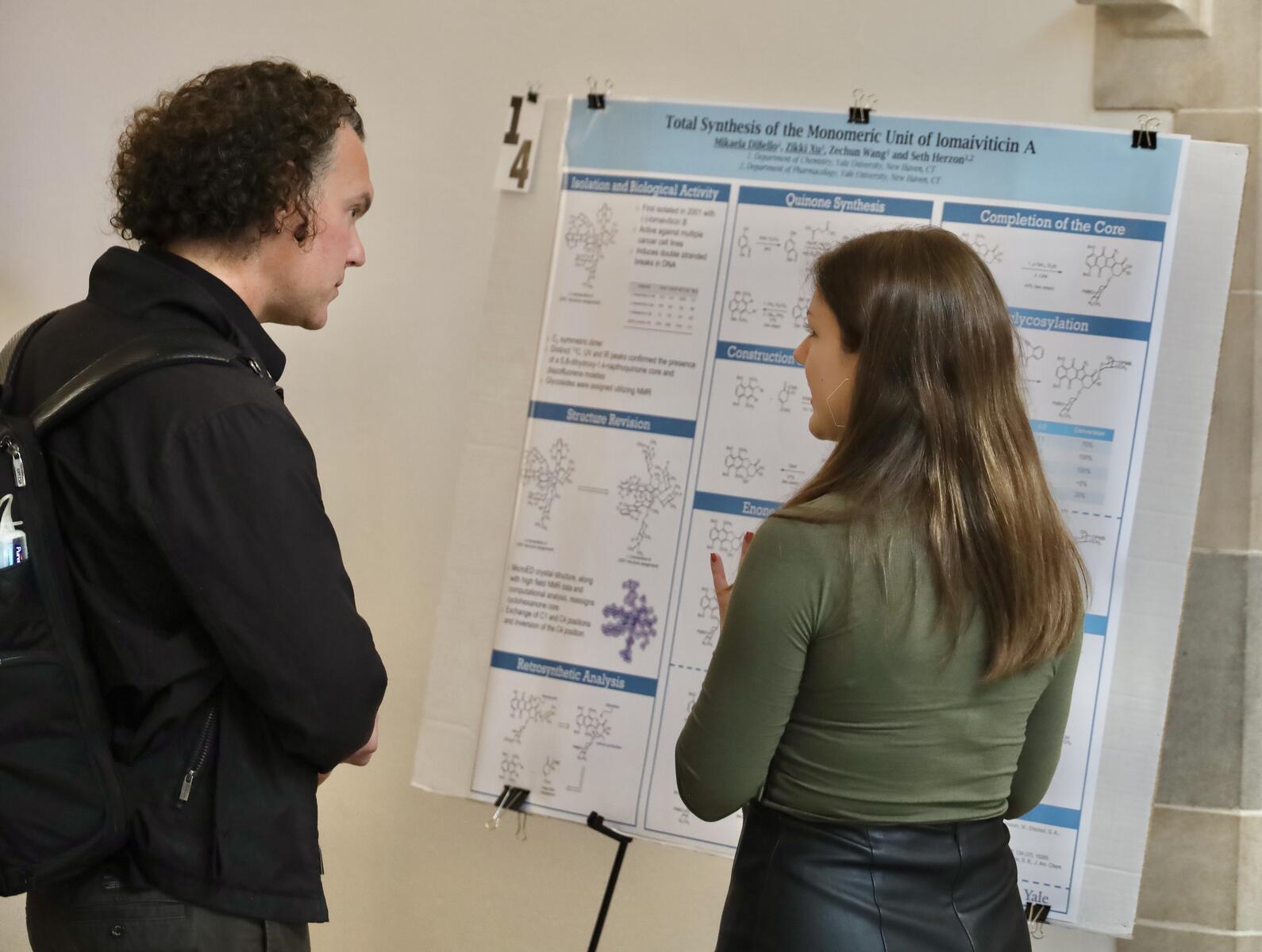 Man and woman chatting and looking at research poster