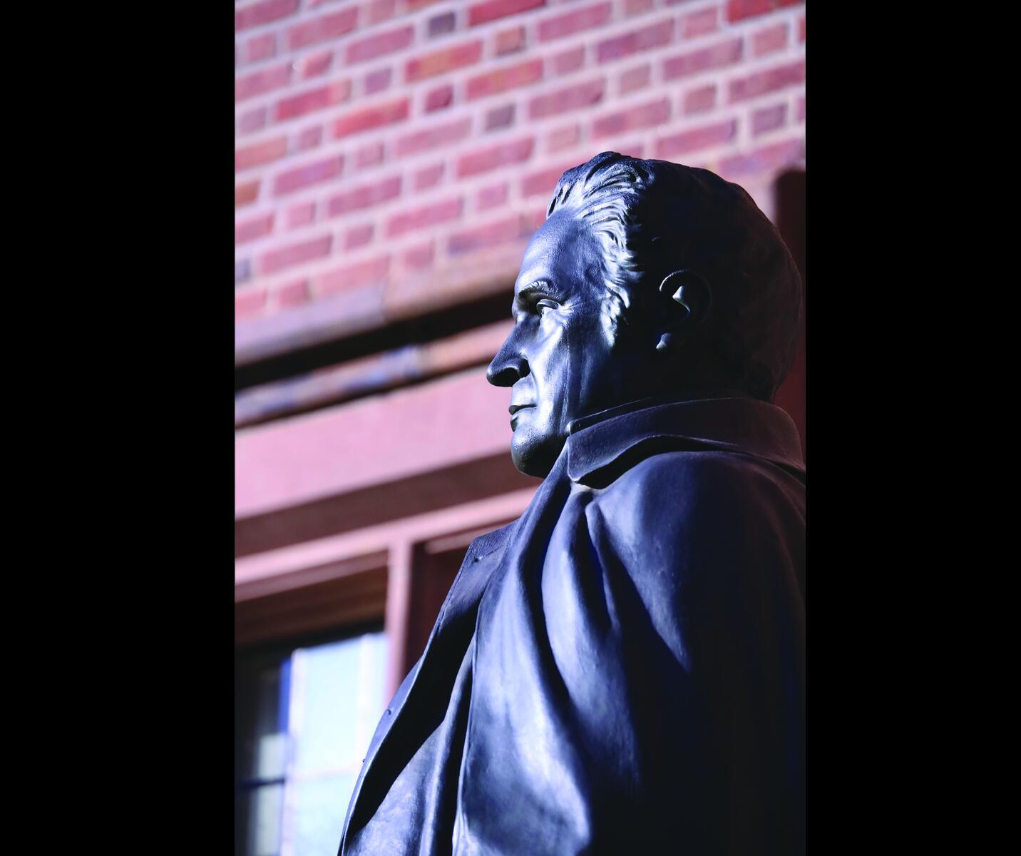 Metal bust of a historical figure against brick wall